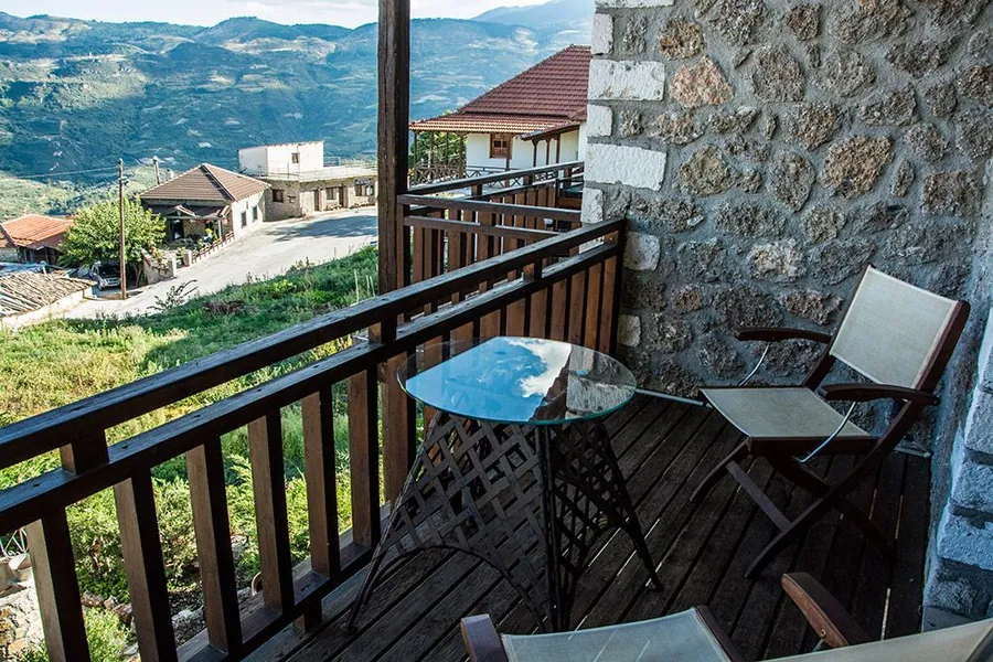 Ξύλινο μπαλκόνι με τραπεζάκι και θέα στο χωριό και τα βουνά