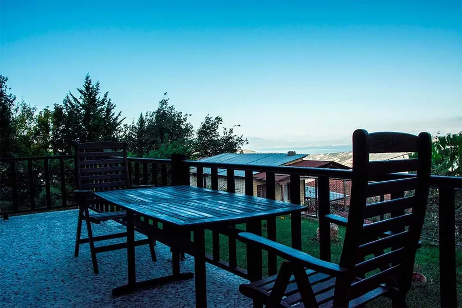 Μπαλκόνι με ξύλινο τραπέζι και καρέκλες, ανάμεσα στα έλατα